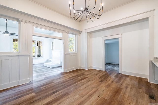 unfurnished living room with ceiling fan with notable chandelier, wood-type flooring, and a healthy amount of sunlight