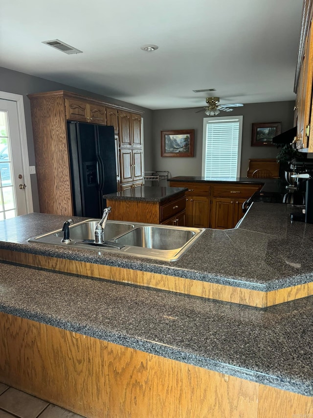 kitchen with sink, kitchen peninsula, black refrigerator with ice dispenser, and ceiling fan