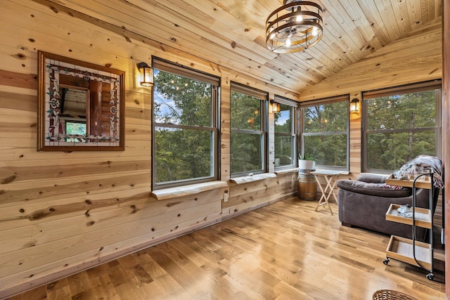 sunroom featuring lofted ceiling, plenty of natural light, an inviting chandelier, and wooden ceiling