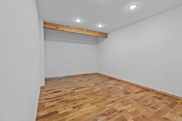 unfurnished room with wood-type flooring and beam ceiling