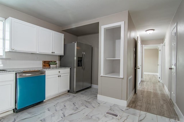 kitchen featuring white cabinets, appliances with stainless steel finishes, light stone counters, and light hardwood / wood-style floors