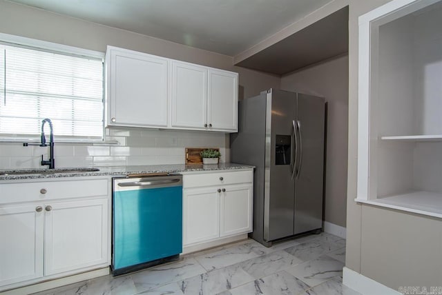 kitchen with white cabinets, light stone countertops, stainless steel appliances, sink, and tasteful backsplash