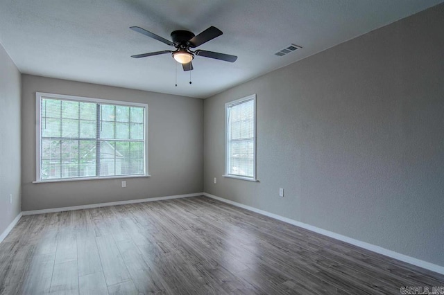 unfurnished room featuring ceiling fan, dark hardwood / wood-style flooring, and a healthy amount of sunlight