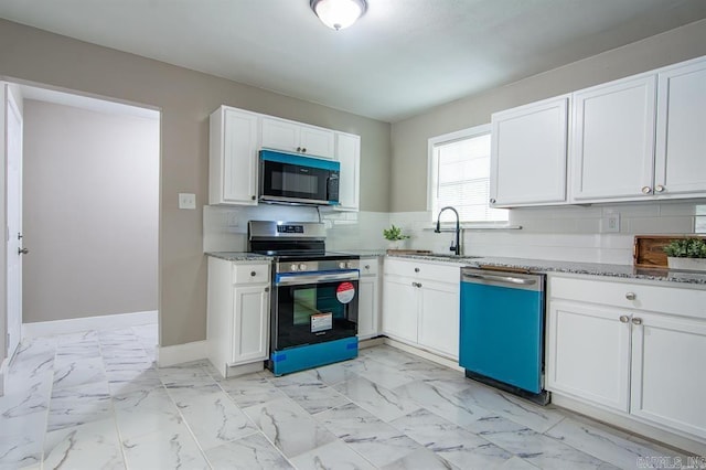 kitchen featuring appliances with stainless steel finishes, white cabinetry, light stone counters, and sink