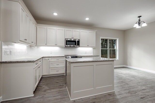 kitchen with dark wood finished floors, white cabinets, stainless steel appliances, and tasteful backsplash