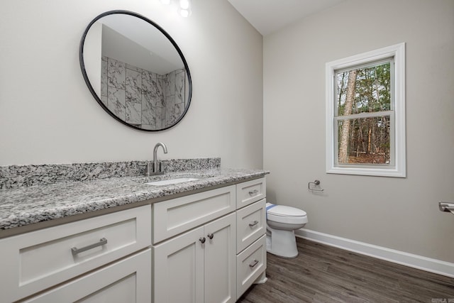 bathroom featuring toilet, vanity, baseboards, and wood finished floors