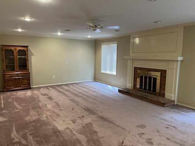 unfurnished living room featuring ceiling fan, a fireplace, crown molding, and light carpet