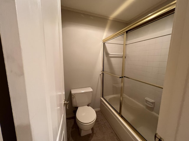 bathroom featuring combined bath / shower with glass door, toilet, and baseboards