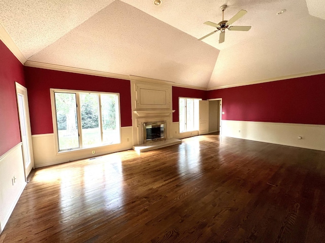 unfurnished living room with lofted ceiling, ornamental molding, wood finished floors, and a large fireplace