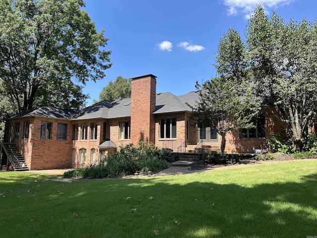 back of house with a lawn, a chimney, and brick siding