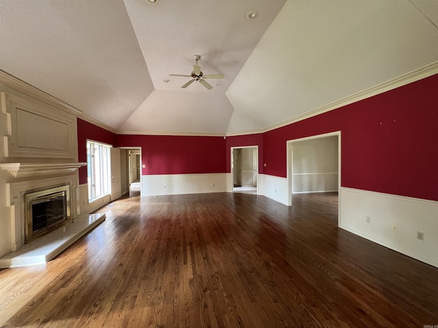 unfurnished living room with ornamental molding, vaulted ceiling, a fireplace, wood finished floors, and a ceiling fan