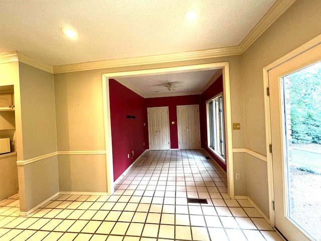 interior space with a textured ceiling, light tile patterned floors, and crown molding