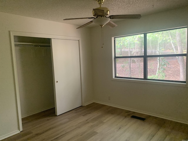 unfurnished bedroom with visible vents, light wood-style flooring, and a textured ceiling