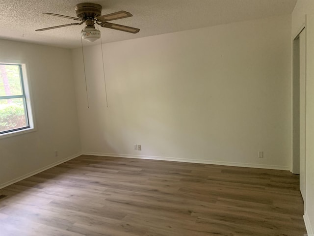 empty room featuring a ceiling fan, a textured ceiling, baseboards, and wood finished floors