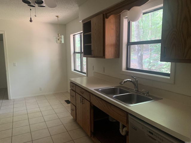 kitchen with light tile patterned floors, white dishwasher, light countertops, a textured ceiling, and a sink