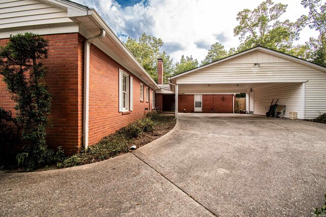 view of home's exterior featuring an attached carport, concrete driveway, and brick siding