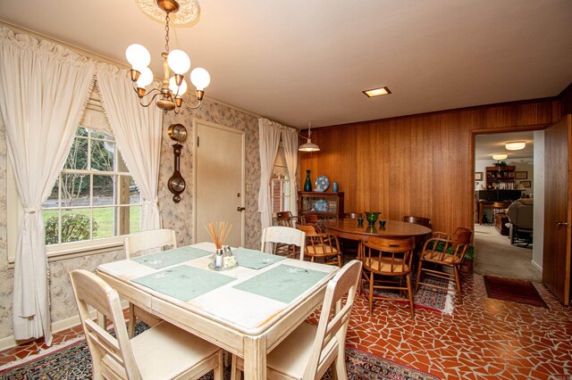 dining area with a notable chandelier and wooden walls