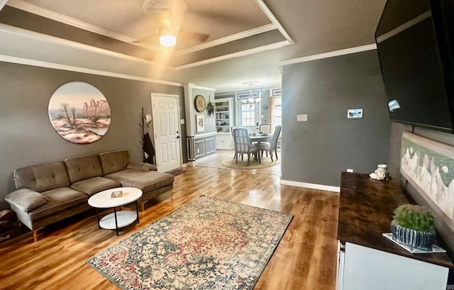 living room with ornamental molding, a raised ceiling, hardwood / wood-style floors, and ceiling fan