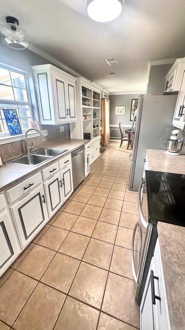 kitchen with crown molding, white cabinetry, light tile patterned floors, sink, and appliances with stainless steel finishes