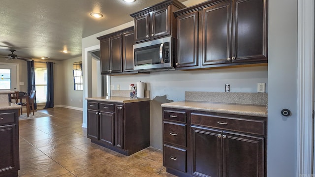 kitchen featuring light countertops, stainless steel microwave, ceiling fan, and dark brown cabinets