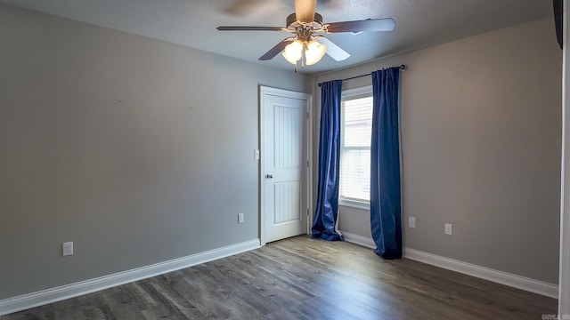 spare room featuring a ceiling fan, dark wood finished floors, and baseboards