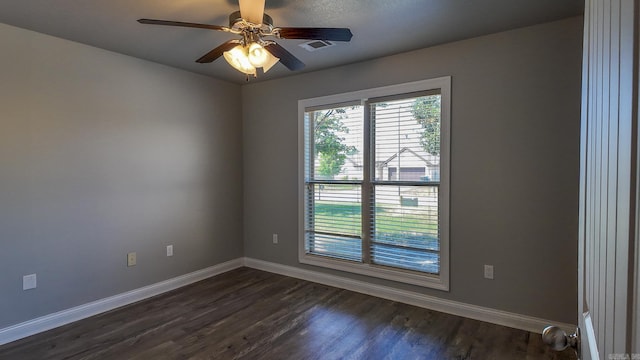 unfurnished room featuring dark wood-style floors, visible vents, and baseboards