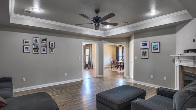 living area with visible vents, a raised ceiling, and ornamental molding