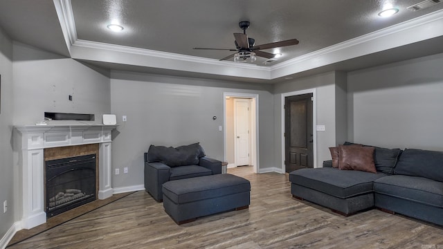 living room with wood finished floors, ornamental molding, a raised ceiling, and visible vents