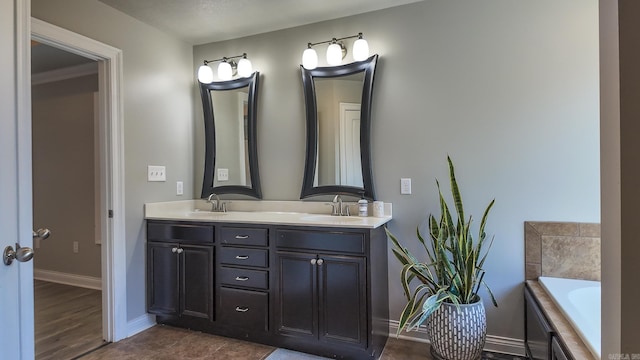 full bathroom with a bath, double vanity, baseboards, and a sink