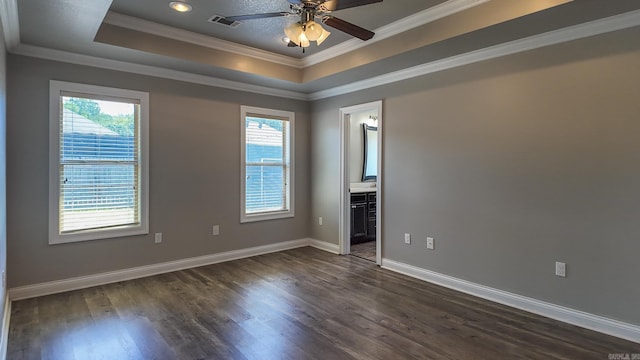 empty room with plenty of natural light, visible vents, a raised ceiling, and dark wood-type flooring