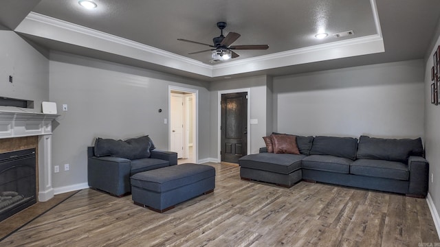 living area with ornamental molding, a tray ceiling, wood finished floors, and visible vents