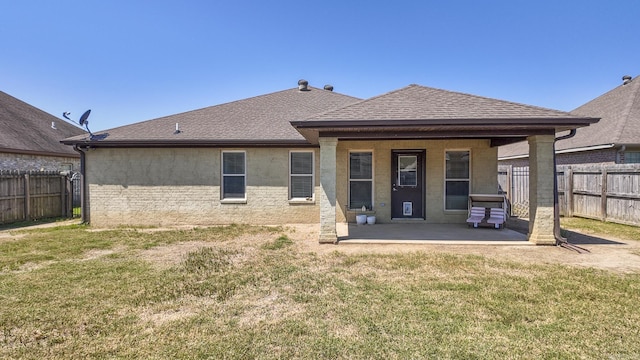 rear view of property with a lawn, roof with shingles, fence, a patio area, and stucco siding