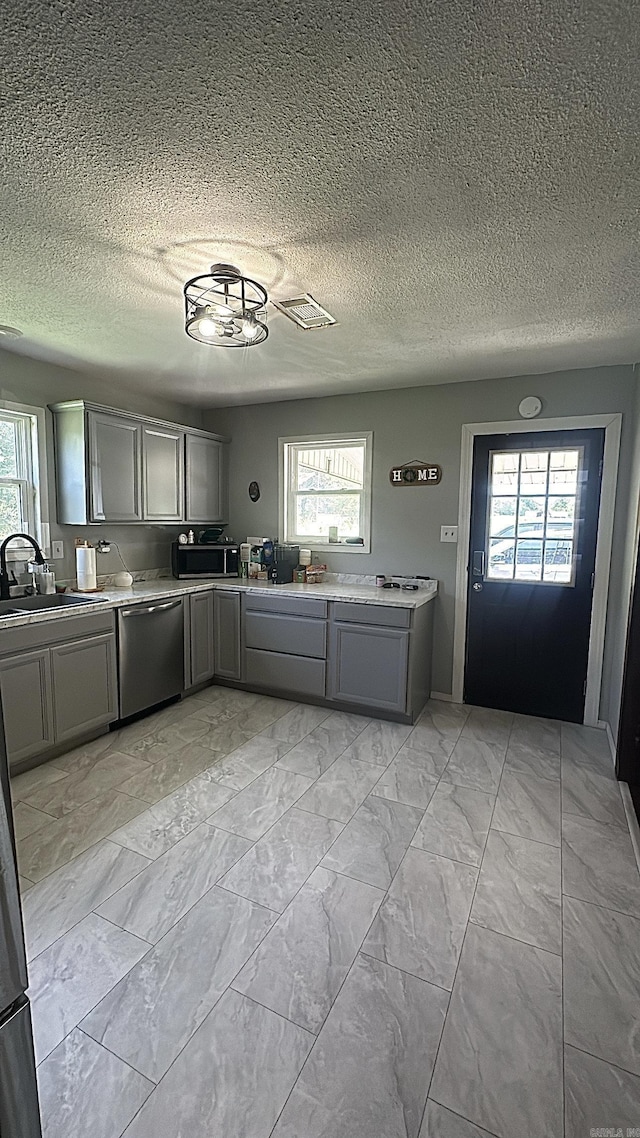 kitchen with marble finish floor, light countertops, stainless steel dishwasher, gray cabinetry, and a sink