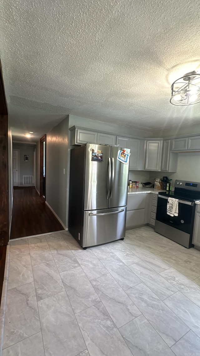 kitchen with a textured ceiling, stainless steel appliances, and gray cabinets