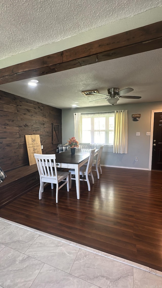 unfurnished dining area featuring a textured ceiling, wood-type flooring, wood walls, and ceiling fan