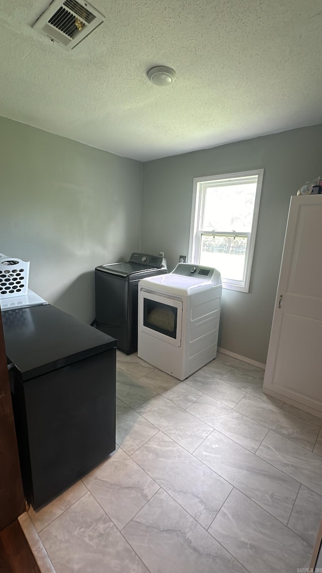 washroom featuring a textured ceiling and washer and dryer