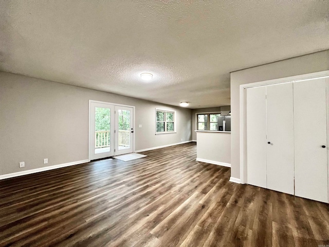 unfurnished living room featuring dark wood-type flooring and a textured ceiling