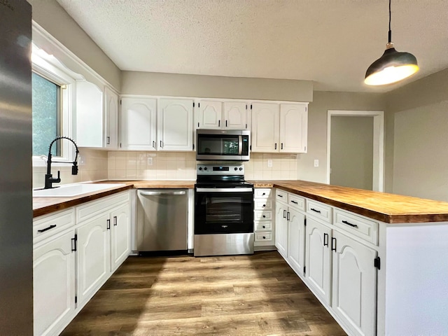 kitchen featuring appliances with stainless steel finishes, white cabinetry, sink, wooden counters, and tasteful backsplash