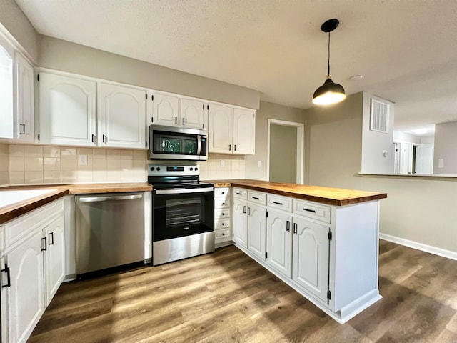 kitchen with appliances with stainless steel finishes, white cabinetry, kitchen peninsula, wooden counters, and tasteful backsplash