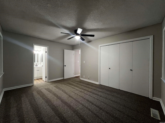 unfurnished bedroom with ensuite bathroom, a closet, carpet, ceiling fan, and a textured ceiling