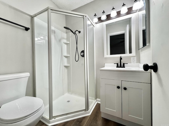 bathroom featuring a textured ceiling, vanity, hardwood / wood-style floors, walk in shower, and toilet