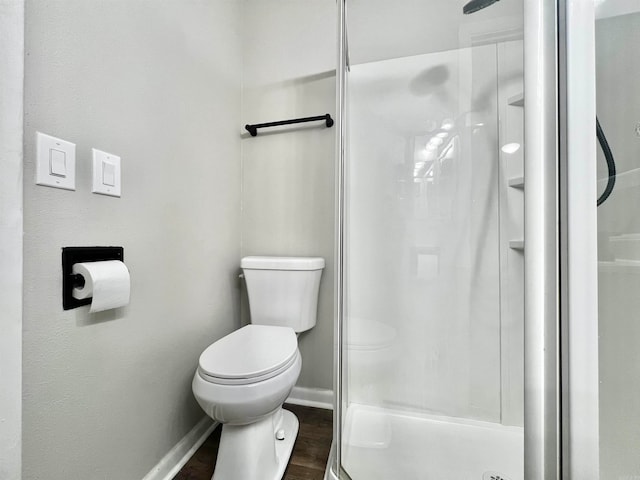 bathroom featuring a shower with door, toilet, and wood-type flooring