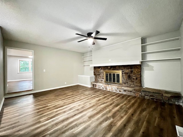 unfurnished living room with a textured ceiling, ceiling fan, hardwood / wood-style floors, and a stone fireplace