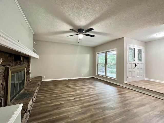 unfurnished living room featuring ceiling fan, a fireplace, wood-type flooring, and a textured ceiling