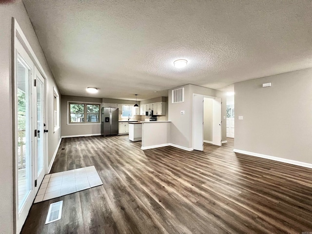 unfurnished living room featuring dark wood-type flooring and a textured ceiling