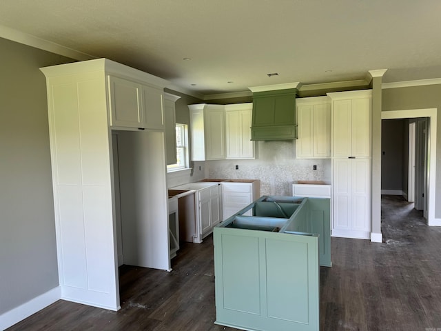 kitchen with white cabinetry, a kitchen island, dark wood-type flooring, and crown molding