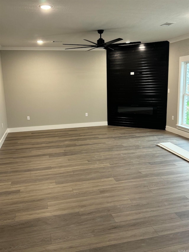 unfurnished room featuring crown molding, a fireplace, ceiling fan, and hardwood / wood-style flooring