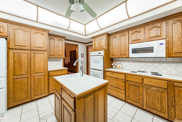 kitchen with white appliances, light tile patterned floors, an island with sink, sink, and ceiling fan