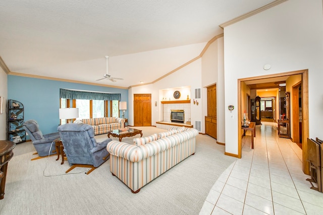 tiled living room with ceiling fan, ornamental molding, high vaulted ceiling, and a fireplace