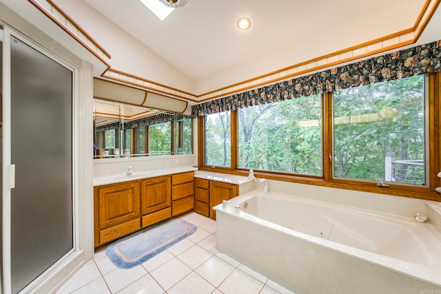 bathroom featuring tile patterned flooring, vaulted ceiling with skylight, separate shower and tub, and vanity